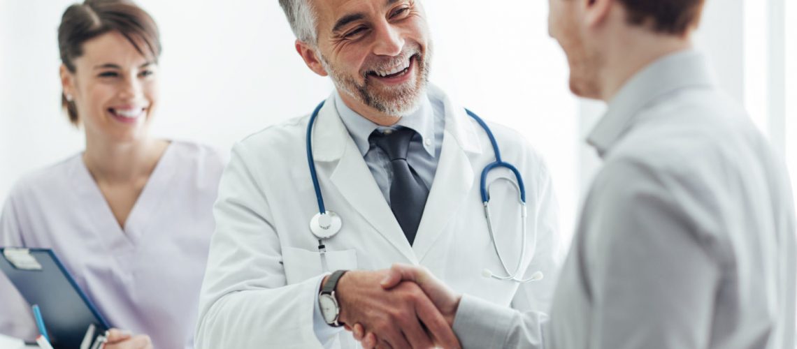 62025951 - smiling doctor at the clinic giving an handshake to his patient, healthcare and professionalism concept
